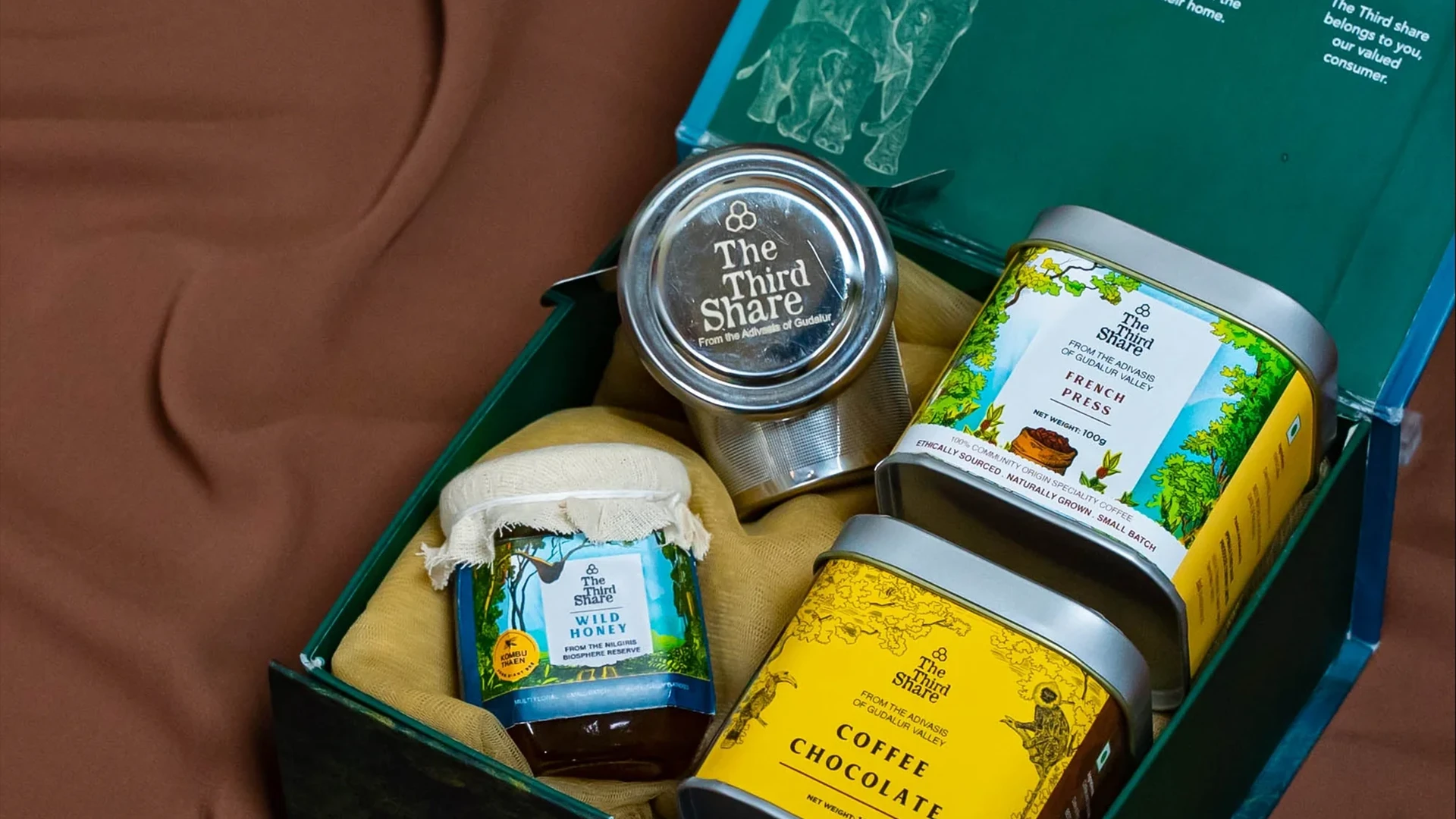 An open The Third Share gift box with wild honey, French press coffee and coffee chocolate
